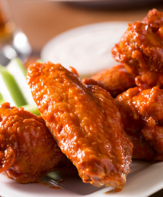 Wings on a plate with celery in the background.