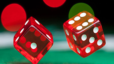pair of red dice being thrown on green craps table felt