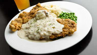 chicken fried steak with gravy, mashed potatoes and peas