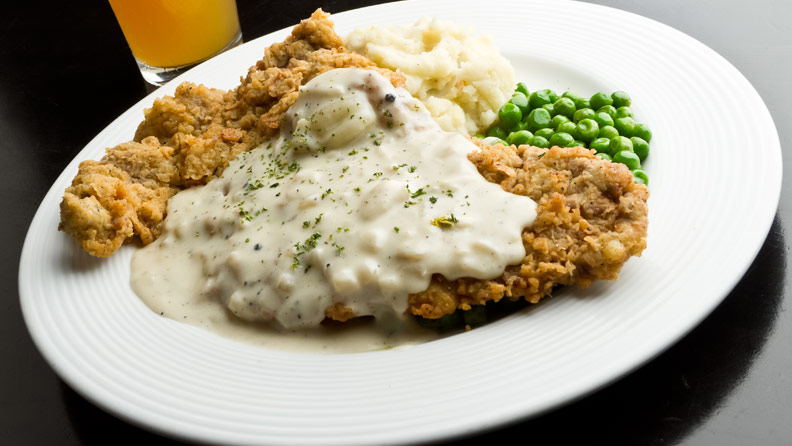chicken fried steak with gravy, mashed potatoes and peas